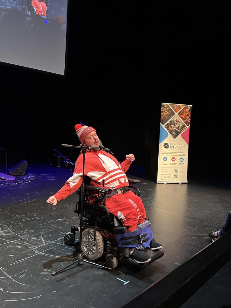 A man in a wheelchair performing comedy on stage.