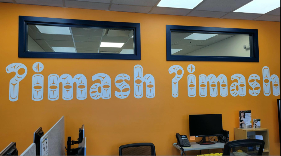 mural featured words of welcome in the Shashishalhem language on a bright orange wall at the WorkBC Centre- Sechelt.
