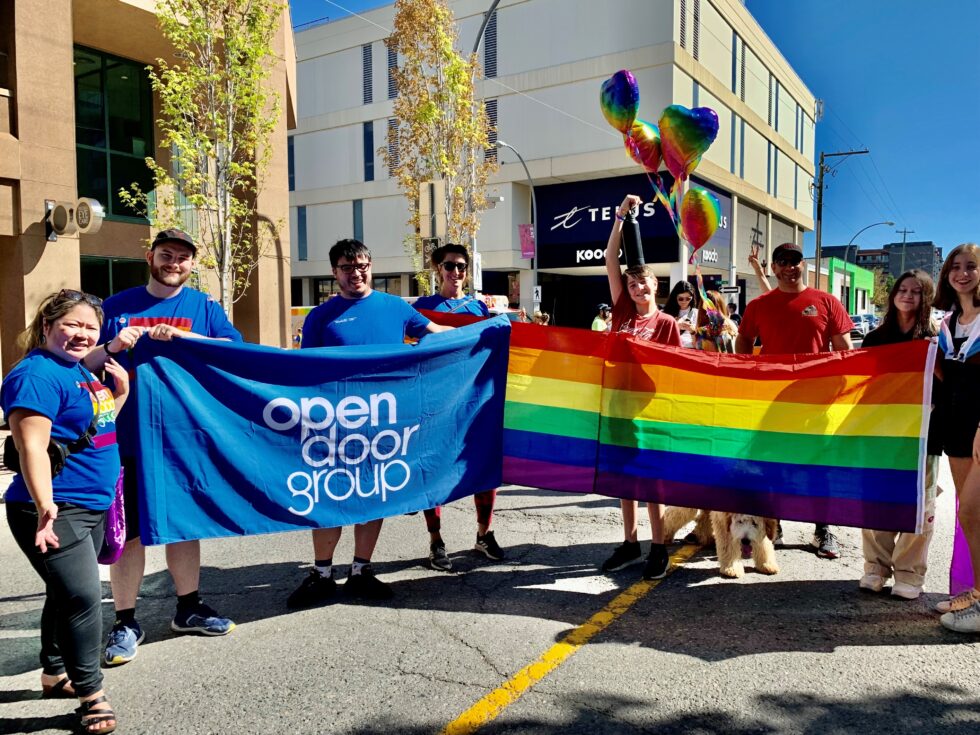  Open Door Group team at the Kamloops Pride Parade. All team members dressed in ODG Happy Pride t-shirts and held ODG banner to walk the parade at downtown Kamloops. From left to right: Louise, David, Devon, Anjali.
