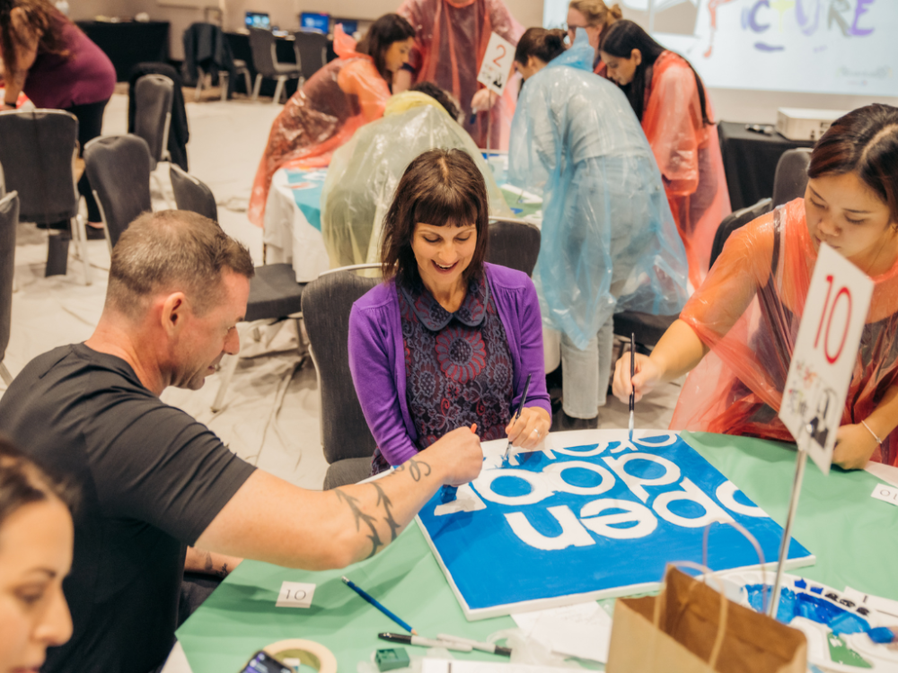 a group of diverse background people painting happily together.